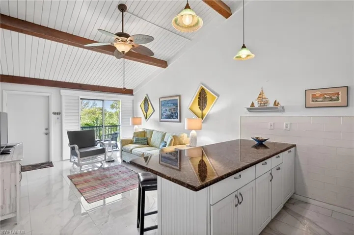 Vaulted ceiling with exposed wood beams, bright white shiplap, and a ceiling fan