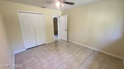 Unfurnished bedroom with ceiling fan, a closet, and light tile patterned floors