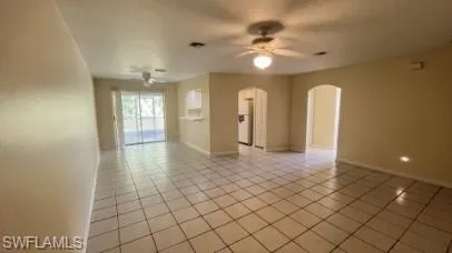Spare room with arched walkways, ceiling fan, and light tile patterned flooring