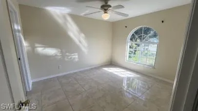 Empty room featuring baseboards and a ceiling fan