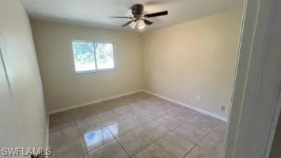 Empty room with a ceiling fan and light tile patterned flooring