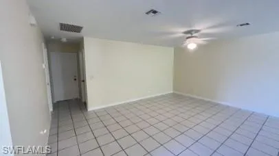 Empty room with a ceiling fan and light tile patterned floors