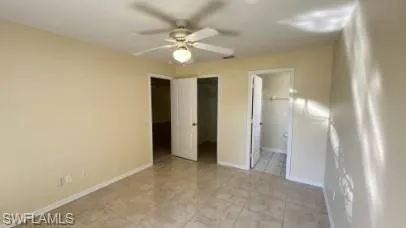 Unfurnished bedroom featuring a walk in closet, a ceiling fan, and ensuite bathroom