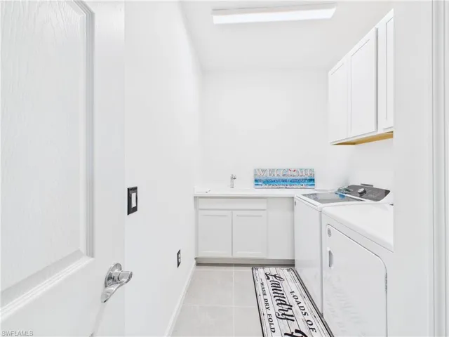 Laundry area featuring cabinet space, light tile patterned floors, and washing machine and dryer