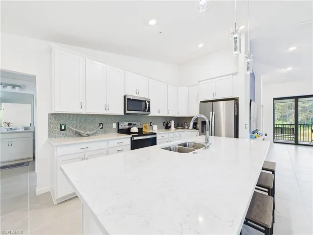Kitchen with white cabinets, light tile patterned floors, light stone countertops, and recessed lighting