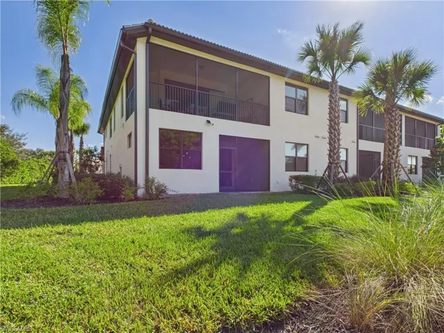 Rear view of property with a yard, stucco siding, and a balcony