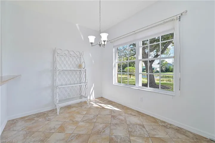 Unfurnished dining area with a chandelier and baseboards