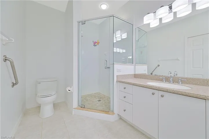 Full bathroom featuring light tile patterned floors, vanity, and a shower stall