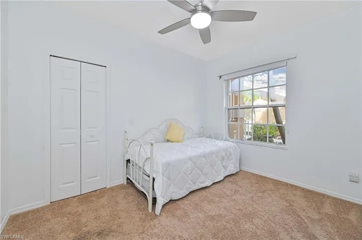 Carpeted bedroom featuring a ceiling fan and a closet