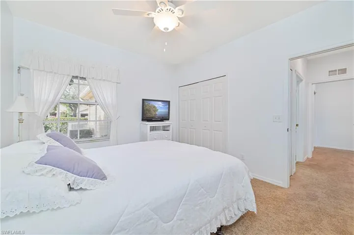 Bedroom with light colored carpet, a closet, and a ceiling fan