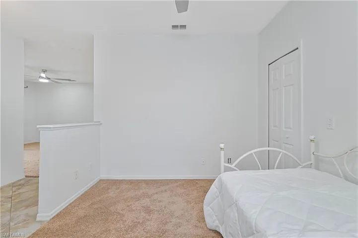 Bedroom featuring light colored carpet, ceiling fan, and a closet