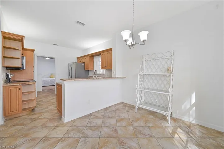 Kitchen featuring open shelves, pendant lighting, a peninsula, a chandelier, and stainless steel fridge with ice dispenser