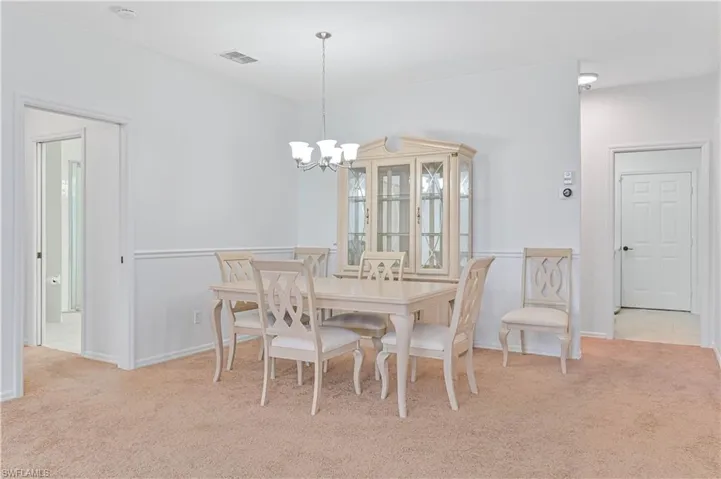 Dining area featuring light colored carpet and a chandelier