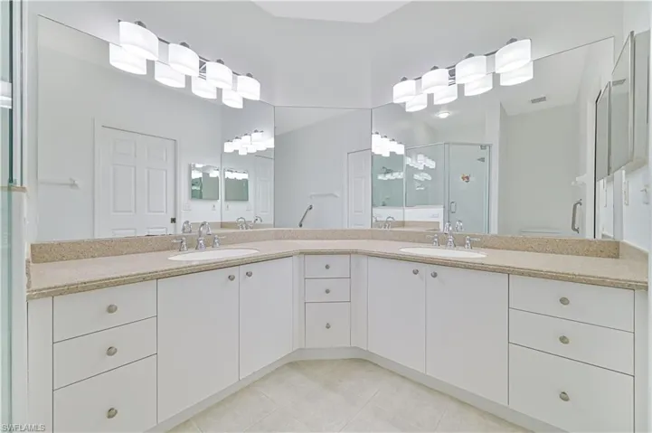 Bathroom with double vanity, a stall shower, and light tile patterned flooring