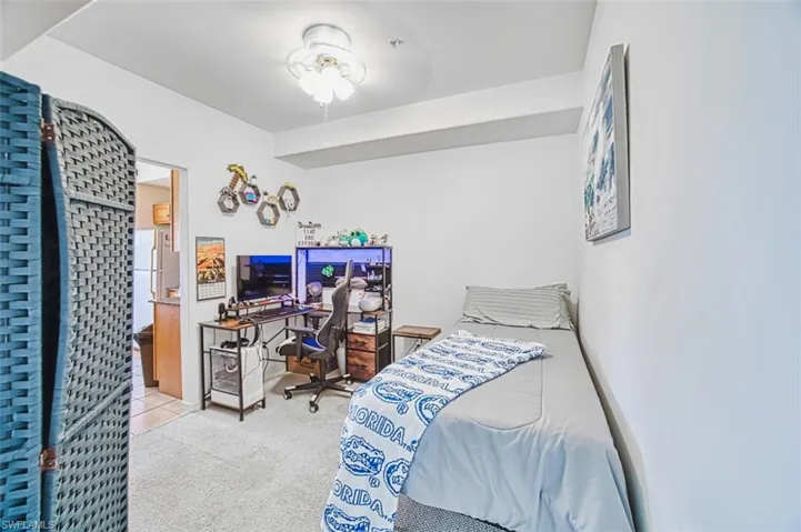 Carpeted bedroom with an office area and freestanding refrigerator