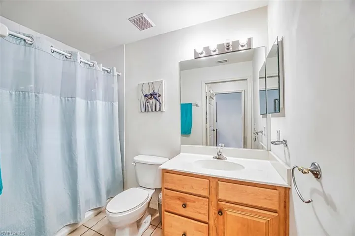 Bathroom with vanity, light tile patterned flooring, and shower / bathtub combination with curtain