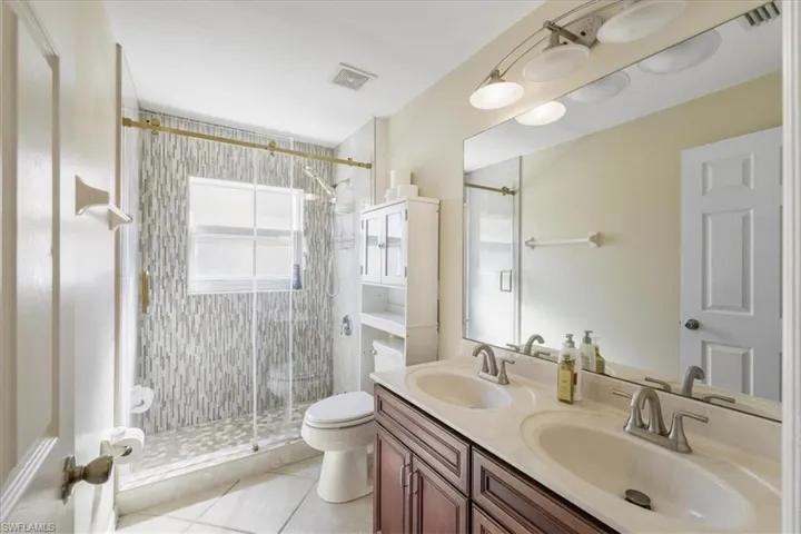 Bathroom with double vanity, a stall shower, and light tile patterned flooring