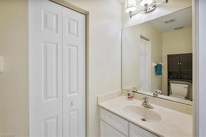 Bathroom with a closet, vanity, and suspended lighting