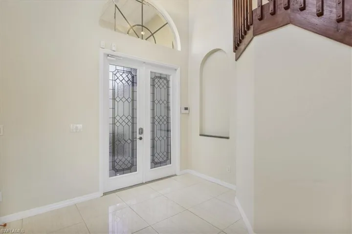 Entryway featuring french doors, light tile patterned flooring, and a high ceiling
