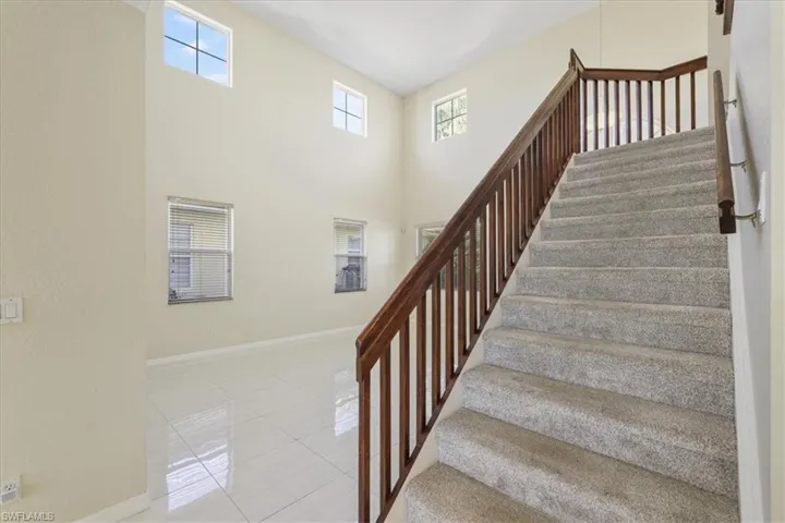 Stairs featuring tile patterned floors, healthy amount of natural light, and a high ceiling