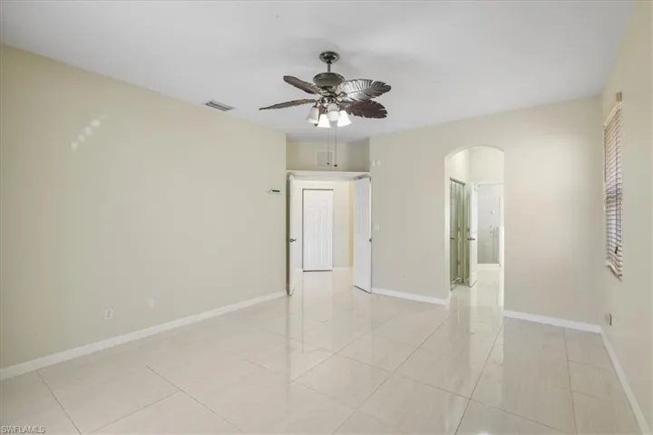 Unfurnished room featuring arched walkways, ceiling fan, and light tile patterned floors