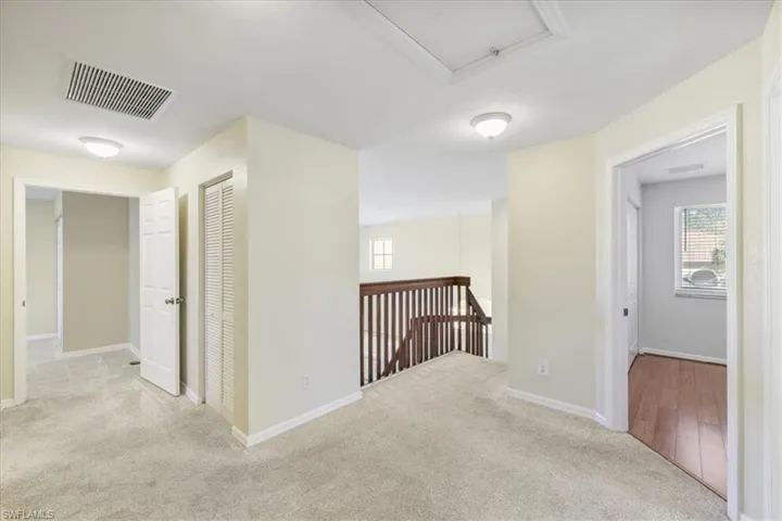 Hallway featuring light carpet and an upstairs landing