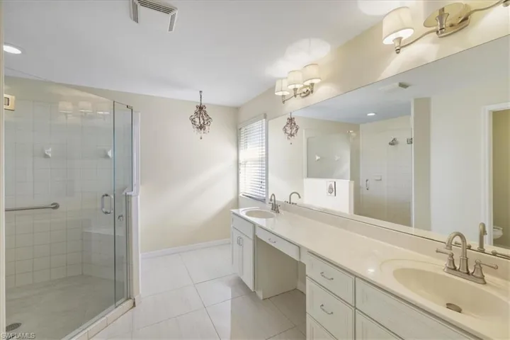Bathroom featuring a stall shower, double vanity, light tile patterned floors, and recessed lighting
