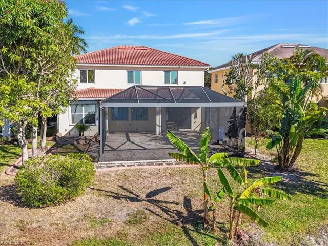 Back of house with a sunroom, glass enclosure, a tile roof, and stucco siding