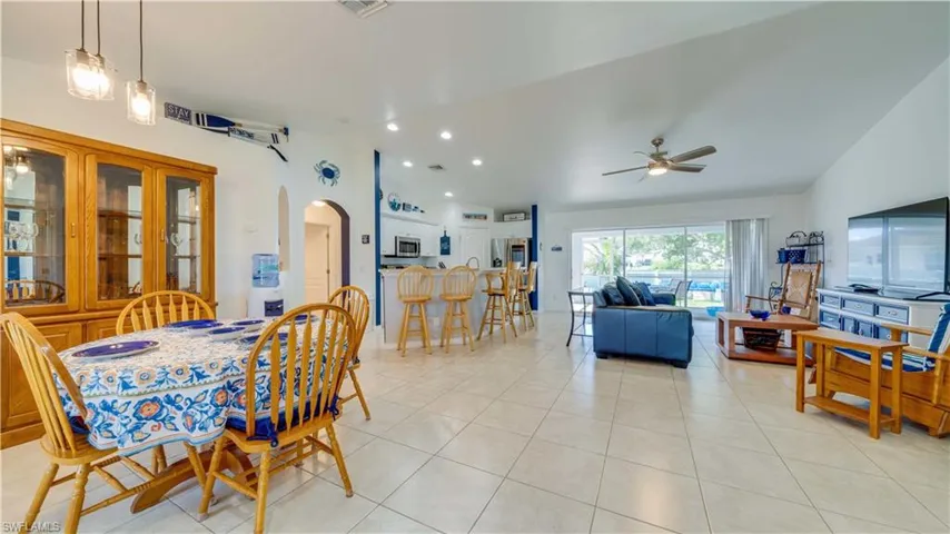 Dining space with vaulted ceiling, arched walkways, light tile patterned floors, recessed lighting, and ceiling fan