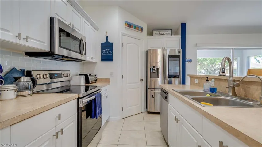 Kitchen with backsplash, stainless steel appliances, and white cabinetry
