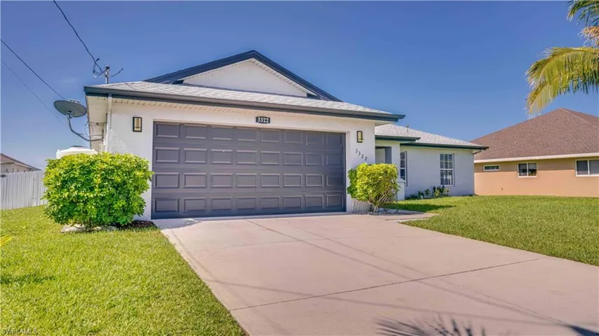 Ranch-style house featuring a front lawn, concrete driveway, stucco siding, and a garage