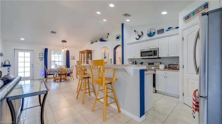 Kitchen with appliances with stainless steel finishes, white cabinetry, light countertops, a kitchen breakfast bar, and recessed lighting