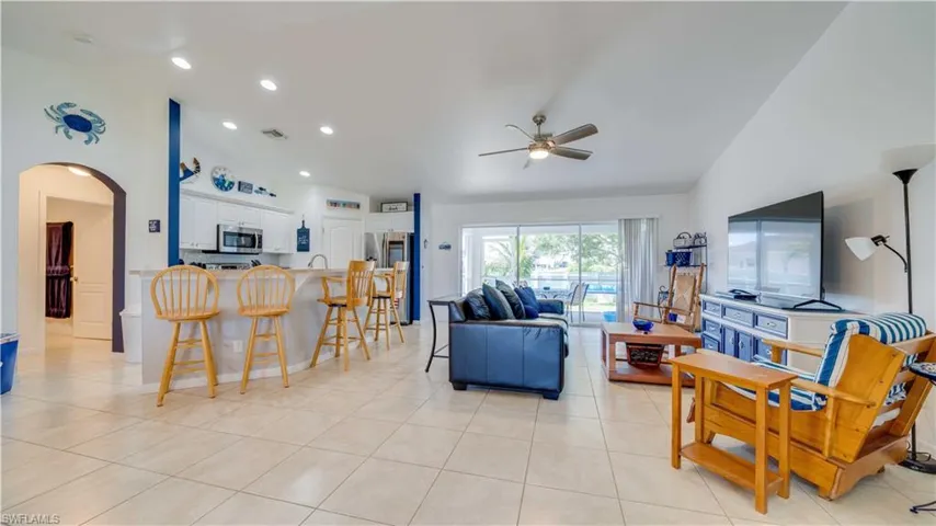 Living area featuring arched walkways, lofted ceiling, light tile patterned floors, recessed lighting, and ceiling fan