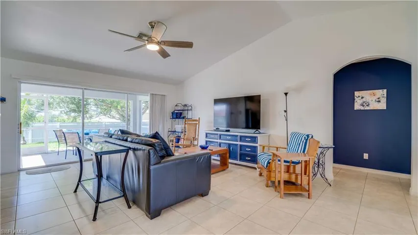 Living room featuring ceiling fan, arched walkways, light tile patterned floors, and high vaulted ceiling
