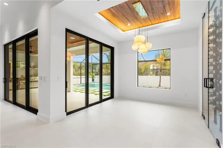 ELEGANT FORMAL DINING ROOM w/ FLAT WOODEN CEILING, designer lighting & 9-ft-tall, TINTED SLIDING DOORS leading to SCREENED LANAI & large PICTURE WINDOW offer views of POOL & SPA.