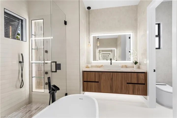 The master bathroom exudes luxury with its spa design, featuring a soaking tub, walk-in shower, dual vanities, and high-end finishes.