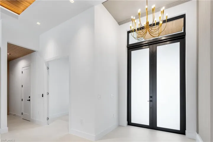 ENTER FRONT-COLUMN PORCH w/ OVERSIZED WRAPAROUND IMPACT-RESISTANT GLASS WALL into IMPRESSIVE FOYER w/ stylish ACOUSTIC PANELING FLOWING into LATERAL WALLS, complemented by 10-ft DOUBLE-TINTED DOORS.