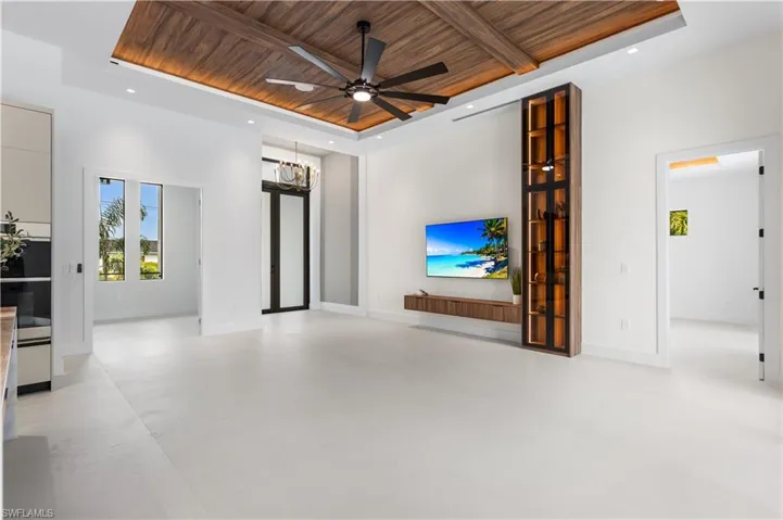AWE-INSPIRING LIVING ROOM w/ 16-ft cove ceiling, FLAT WOODEN PANELS, WALLPAPERED FEATURE WALL w/ cabinets & LED-LIT SHELVING