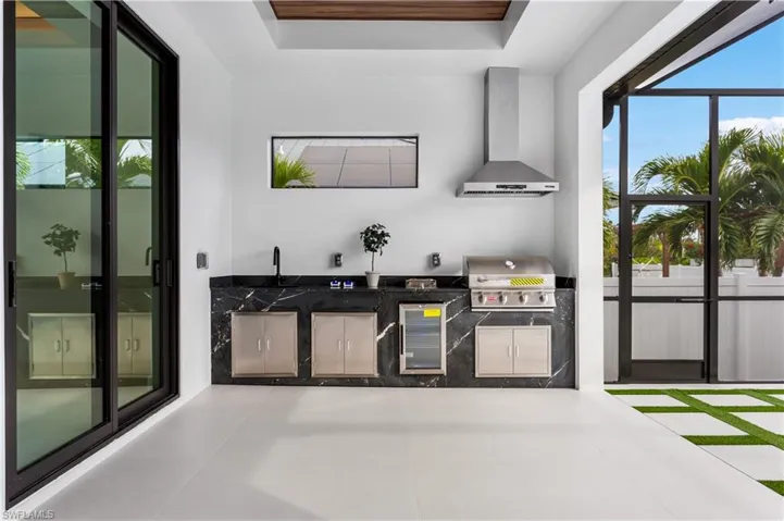 OUTDOOR KITCHEN features SS BULL 4-BURNER propane grill, SIDE BURNER, mini-refrigerator & commercial sink.