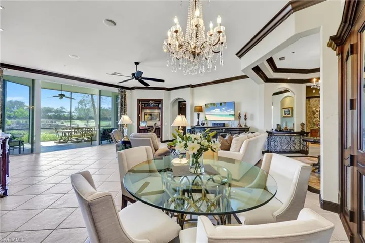 Dining room featuring arched walkways, hanging lights, expansive windows, light tile patterned flooring, and a ceiling fan