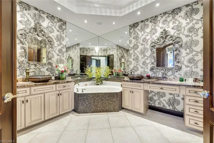 Full bathroom with a garden tub, two vanities, light tile patterned floors, and recessed lighting