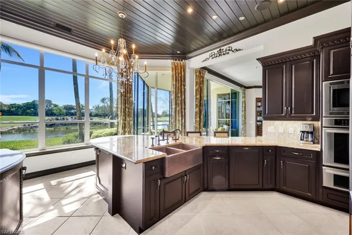 Kitchen featuring dark wood finish cabinetry, stainless steel appliances, a peninsula, plenty of natural light, and crown molding