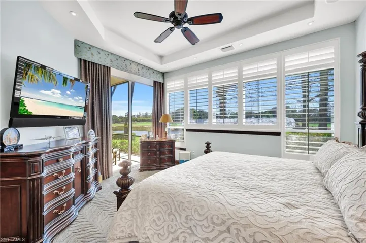 Bedroom featuring access to exterior, a ceiling fan, light carpet, and a tray ceiling