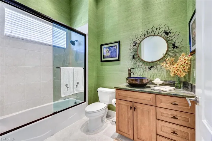 Full bathroom featuring vanity, enclosed tub / shower combo, and wallpapered walls