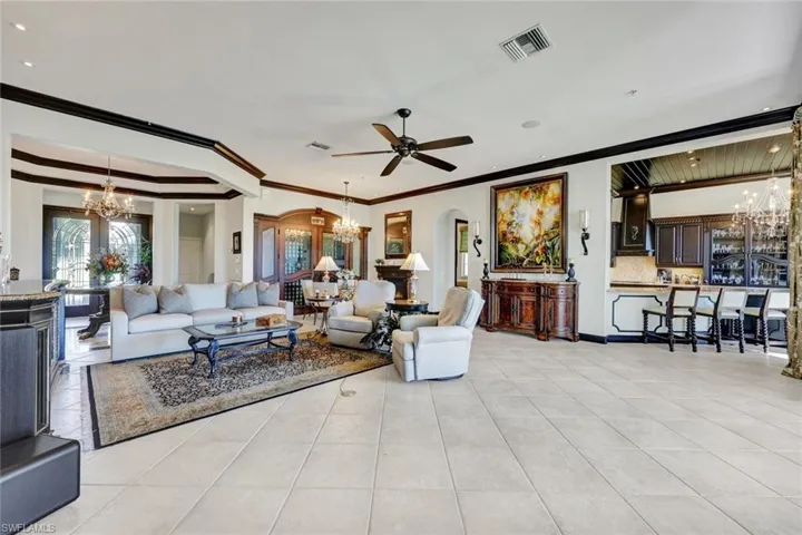Living room with hanging lights, arched walkways, ornamental molding, and a ceiling fan