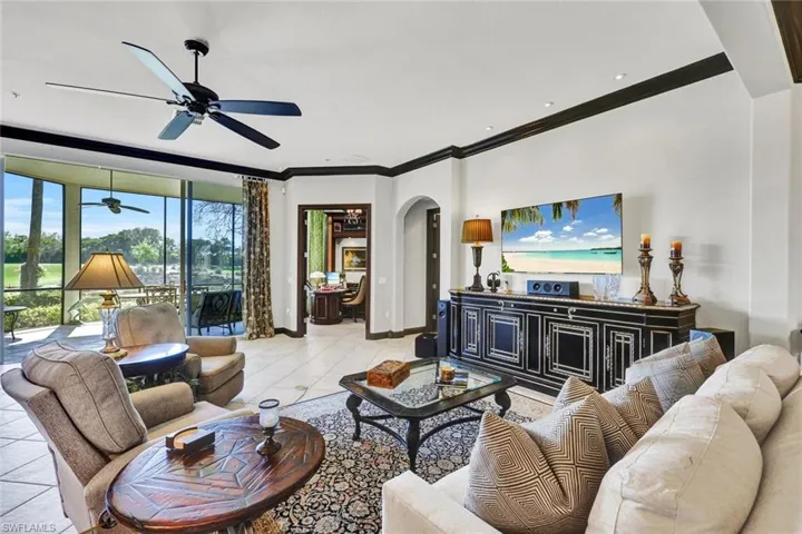 Living room featuring arched walkways, a ceiling fan, crown molding, and light tile patterned floors