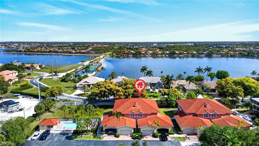 Waterfront community featuring multiple residences with red tile roofs, attached garages, and lush landscaping