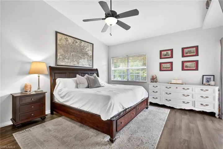 Primary Bedroom with wood-finish flooring, a ceiling fan with integrated lighting, and a large window featuring blinds