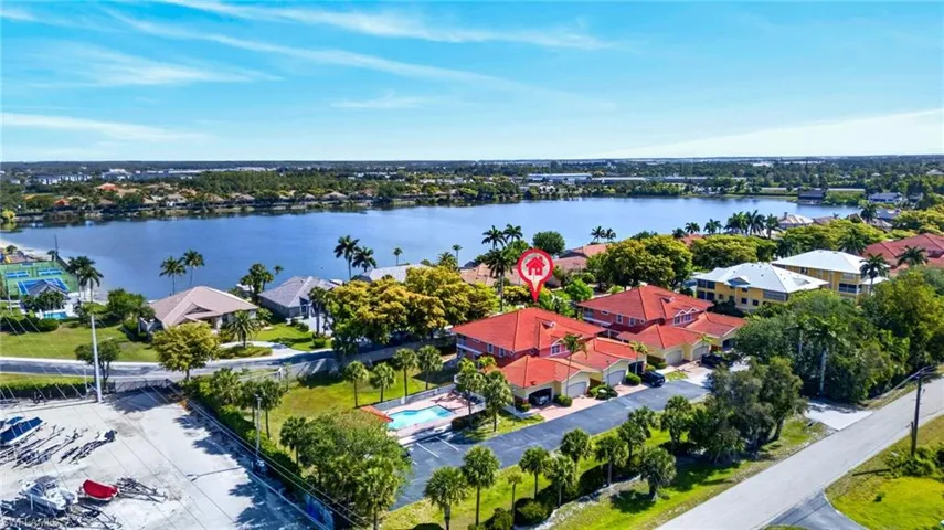 Aerial perspective showcasing the property with a red tile roof and a private pool, set against a large body of water