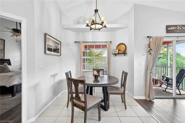 Dining area featuring vaulted ceilings, a window with exterior views, and a bronze-finish chandelier